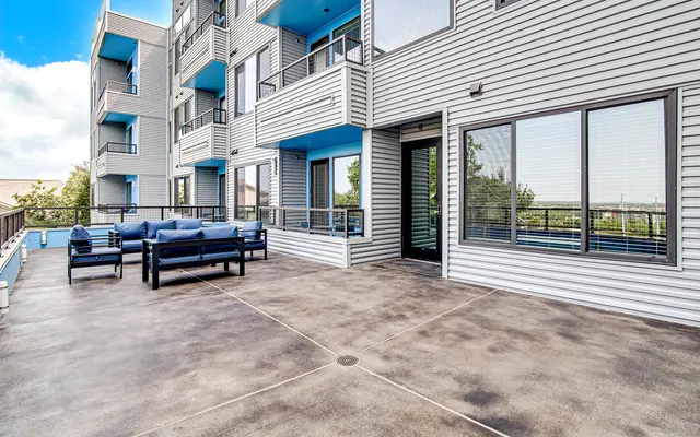 A spacious balcony with modern outdoor furniture and a view of the surrounding area.