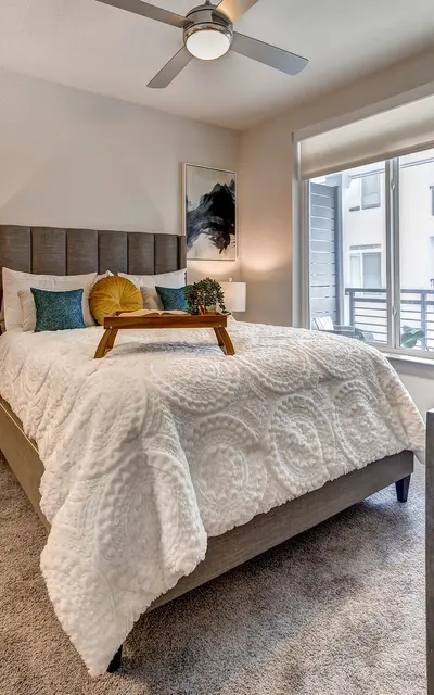 Spacious apartment bedroom at 120 Ninth Street with carpet flooring, large windows, and ceiling fan lighting.