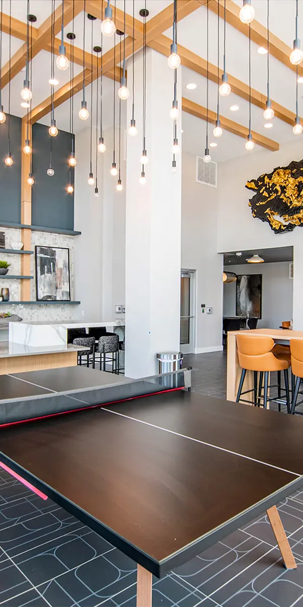 Modern communal space featuring a ping pong table, stylish bar seating, decorative wall art, and a bright, open design.