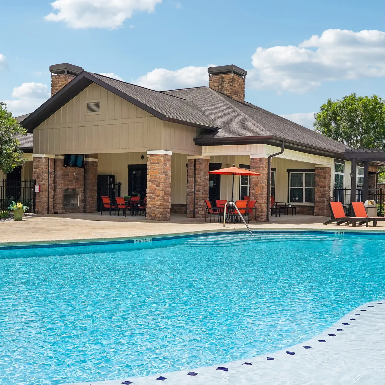Community Pool and Clubhouse A spacious swimming pool area with lounge chairs and a clubhouse in the background.