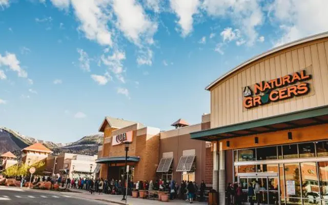 Exterior view of Natural Grocers store with mountains in the background and a clear blue sky.