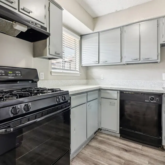 A modern kitchen featuring black appliances, gray cabinets, and a light countertop.