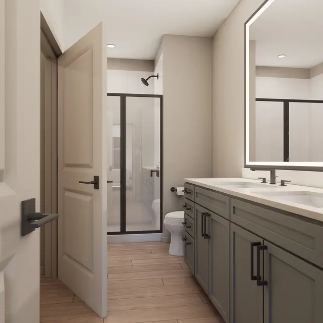 A modern bathroom interior featuring a double sink vanity with dark cabinetry and a large mirror, a glass shower enclosure, and a toilet. The floor is made of wood, enhancing the contemporary aesthetic.