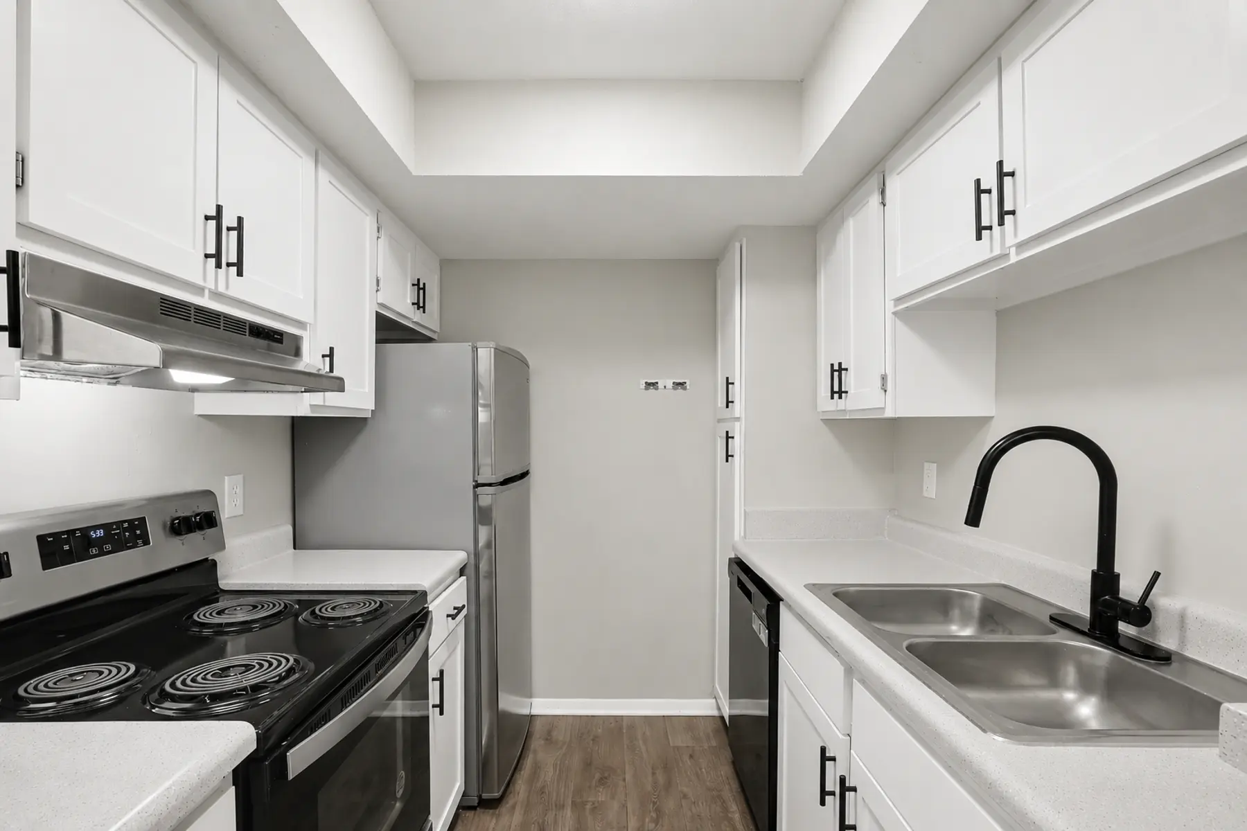 A modern kitchen featuring white cabinets, stainless steel appliances, and a sleek countertop with a double sink.