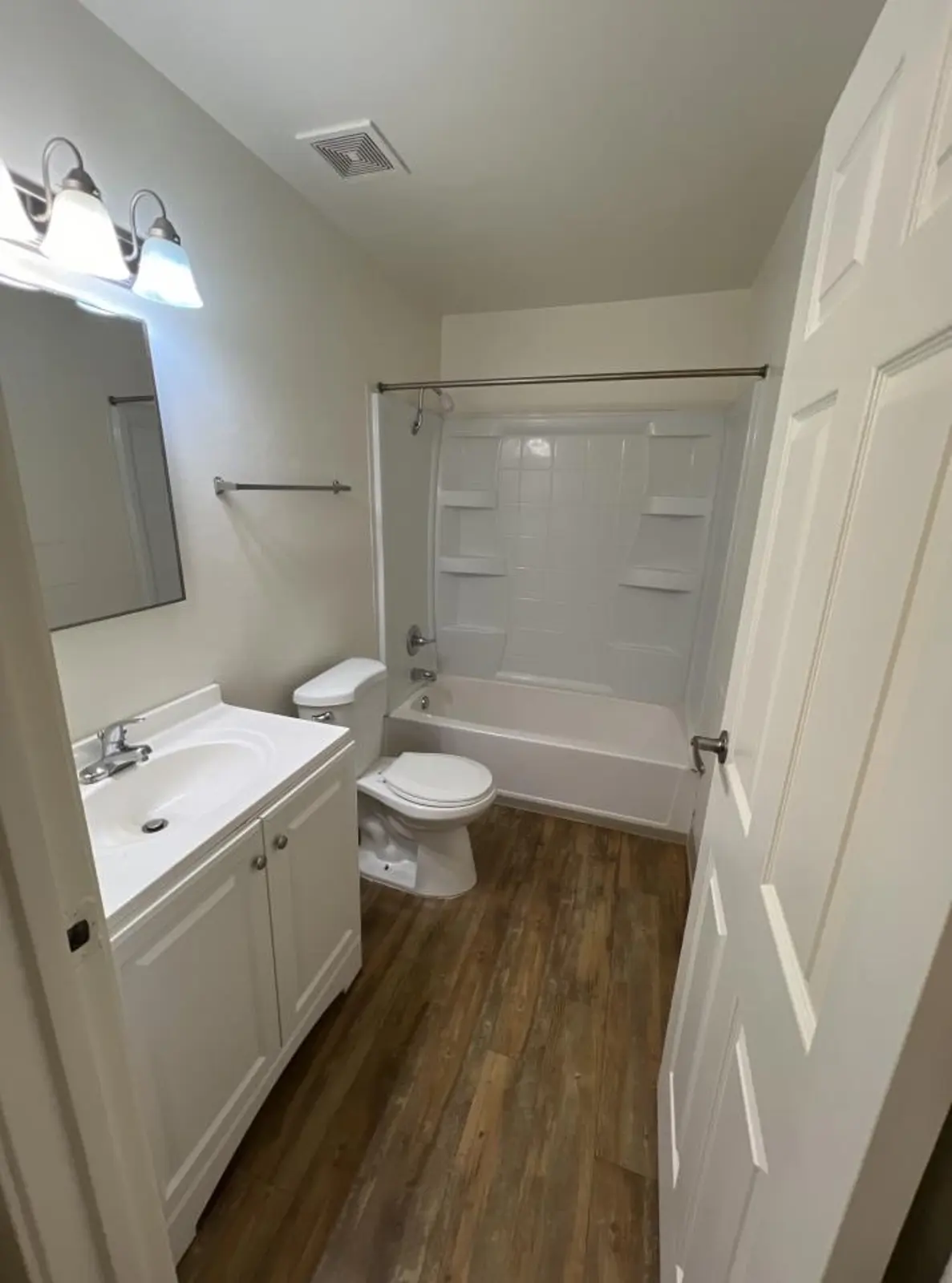 Bathroom viewed toward the tub and shower, beside a vanity and toilet.