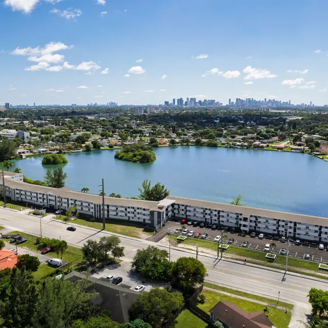 Aerial view of a lake with surrounding greenery and apartment buildings