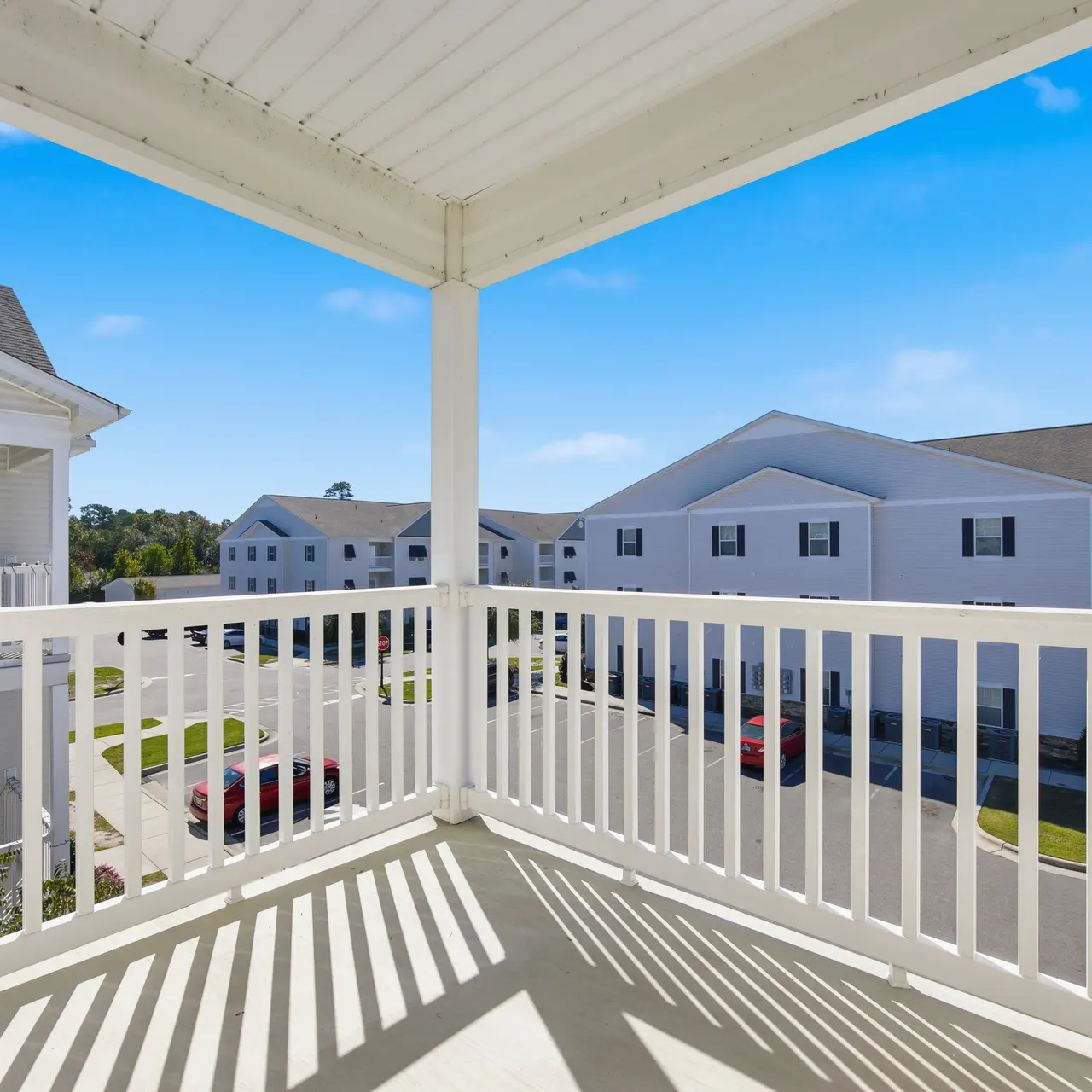 View from a balcony overlooking a residential area with blue sky and scattered clouds.