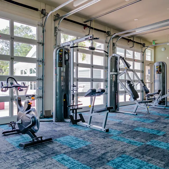 ShoreView A fitness center with three garage-style doors, weight machines, an exercise bicycle, and a water station.