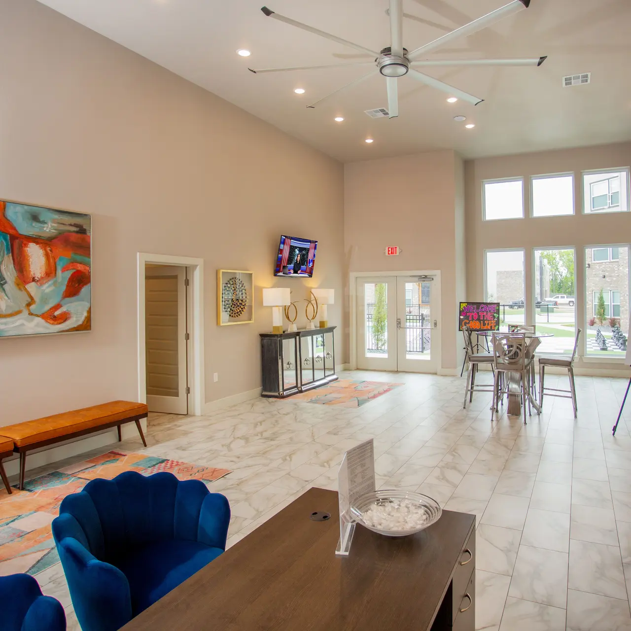 Clubhouse Modern art gallery interior with abstract paintings, blue armchairs, and a wooden bench.