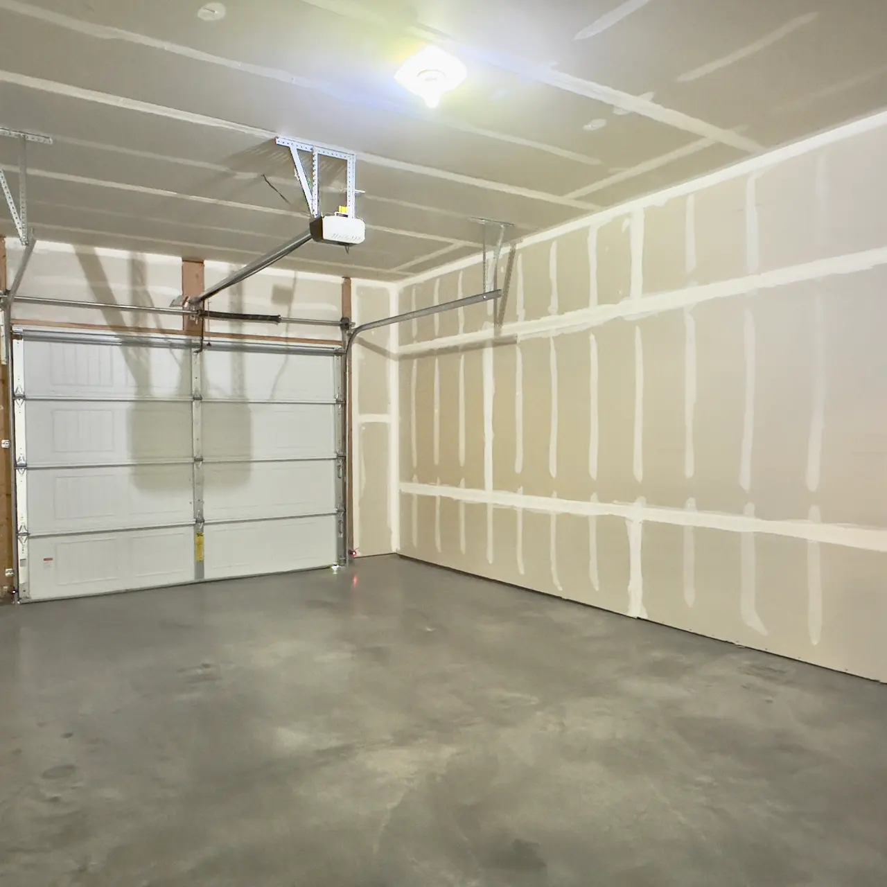 apartment garage Spacious garage with room for vehicles and storage, featuring a sturdy door, ample lighting.