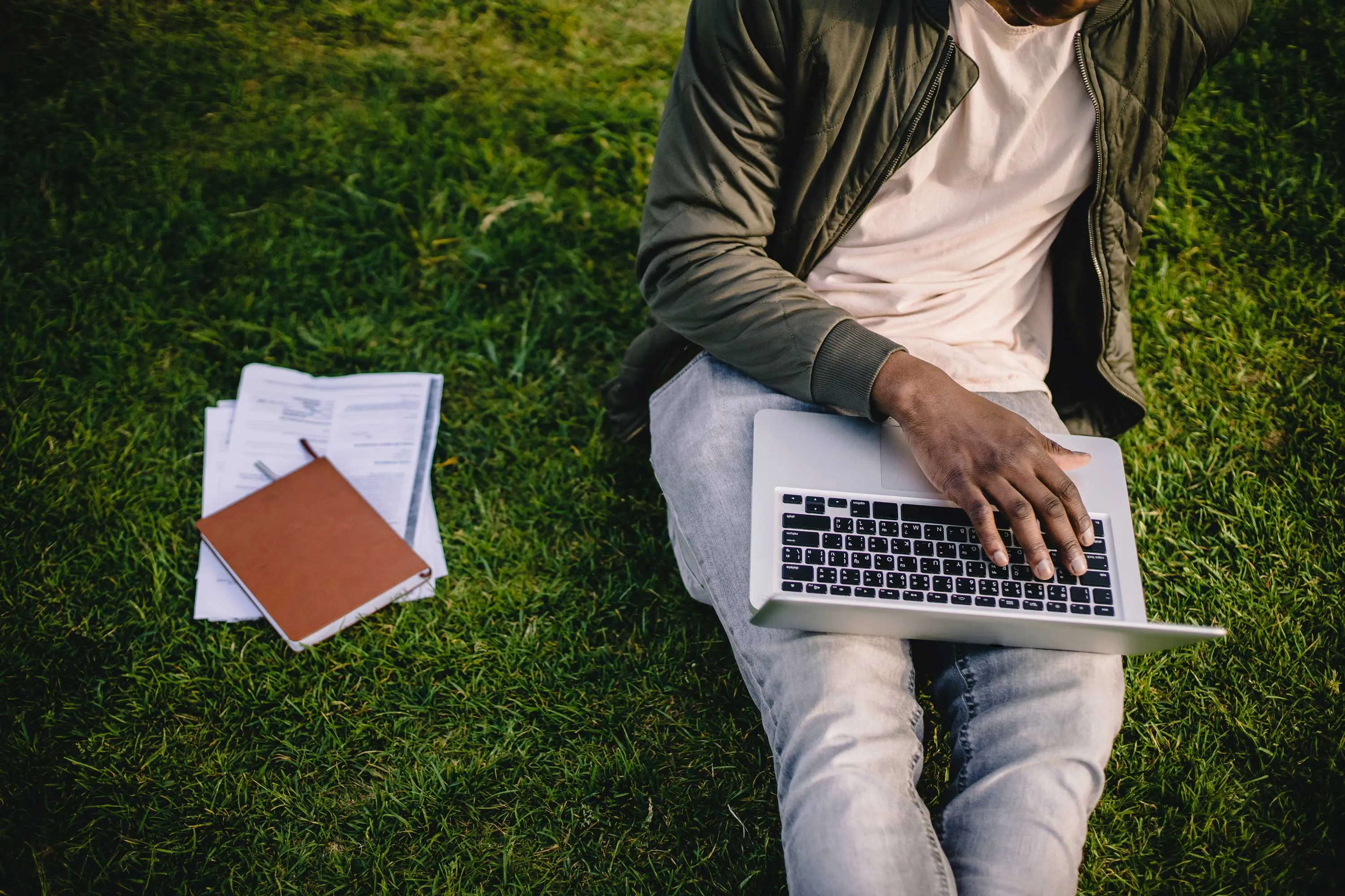 Man sitting on the grass with a laptop in his lap