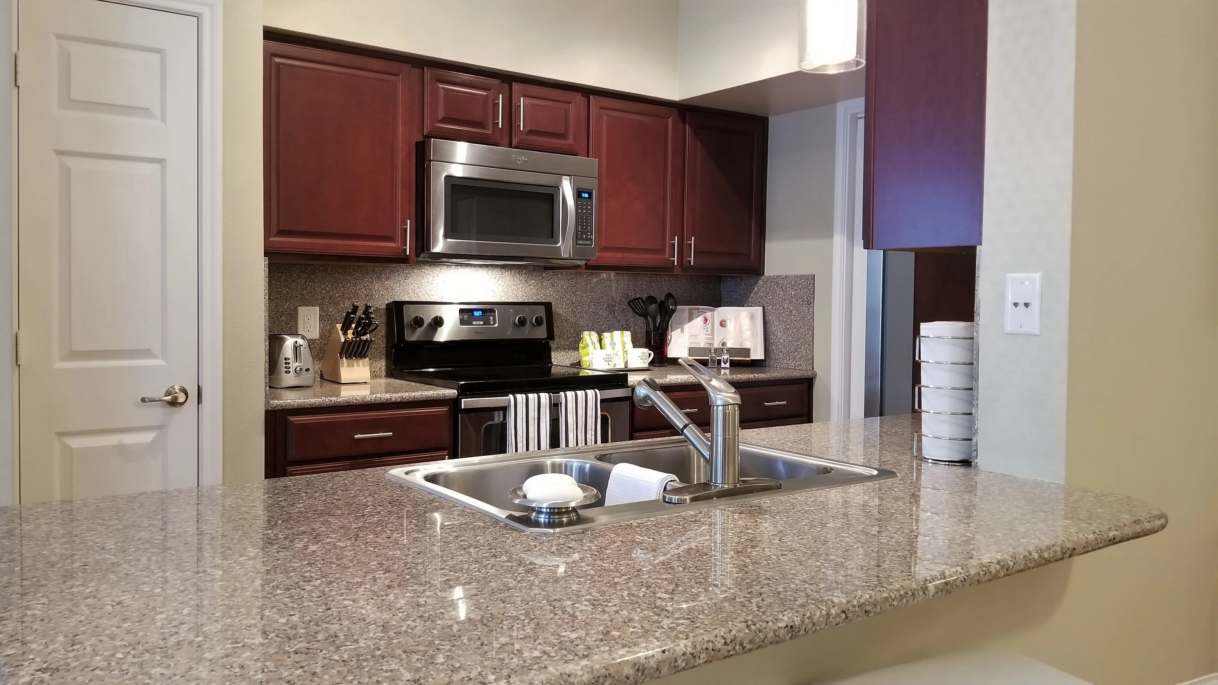 Stylish Modern Kitchen Interior A modern kitchen featuring dark wood cabinets, a granite countertop, stainless steel appliances, and a sink with a faucet.