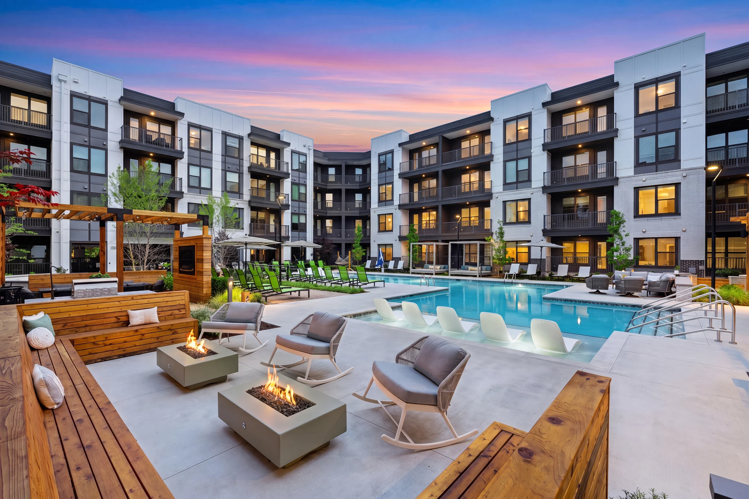 Stylish Apartment Community Pool Area Outdoor community space featuring a pool, lounge chairs, and seating around fire pits.