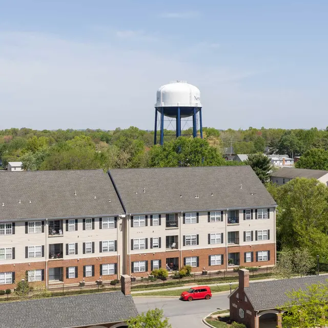 Aerial view of a residential area featuring a water tower in the background and parked cars in the foreground.