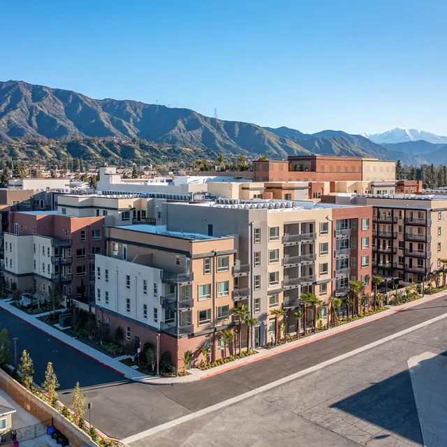 Aerial view of a modern apartment complex with surrounding mountains in the background.
