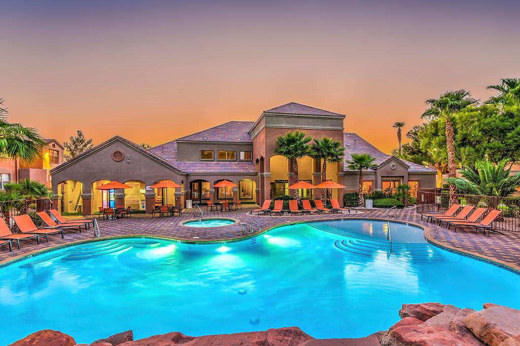 Sunset Pool Area with Lounge Chairs A beautifully landscaped pool area surrounded by lounge chairs and palm trees at sunset. The inviting water reflects the warm colors of the sky, creating a tranquil atmosphere.