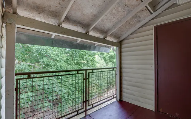 View from a balcony with a railing overlooking greenery.