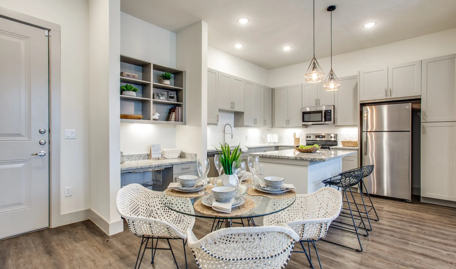 Modern kitchen with dining area, pendant lighting, and stainless steel appliances.