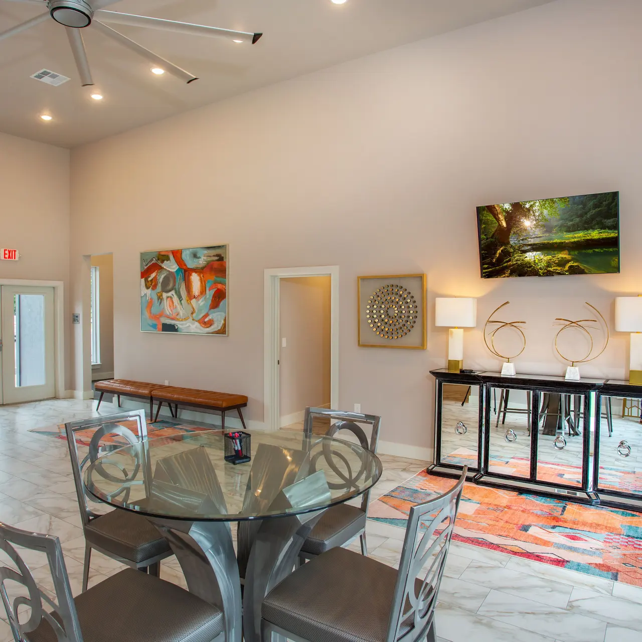 Clubhouse Modern living room with artwork, a glass table, chairs, and decorative lamps.