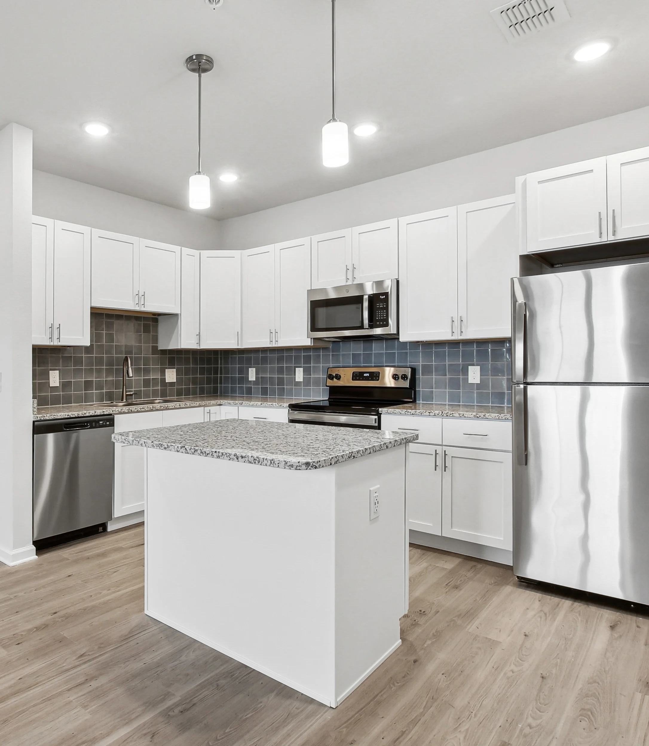EKOS Lake Shadow A modern kitchen featuring white cabinets, stainless steel appliances, and a central island with a granite countertop.