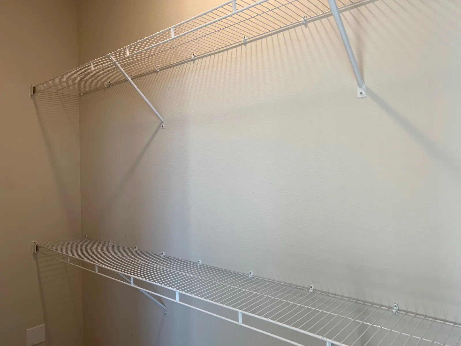 Empty Storage Shelves A view of empty wire storage shelves mounted on a wall in a room.