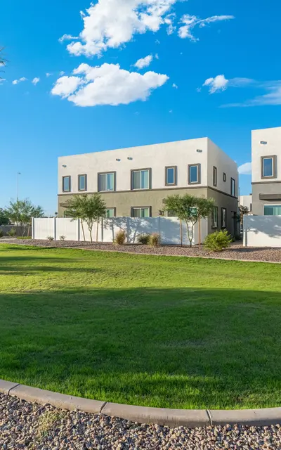 Modern Homes with Green Lawn Two modern houses next to a green lawn under a clear blue sky with some clouds.
