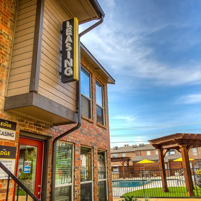 Exterior view of a leasing office with a sign reading 'LEASING', surrounded by a courtyard and pool area.