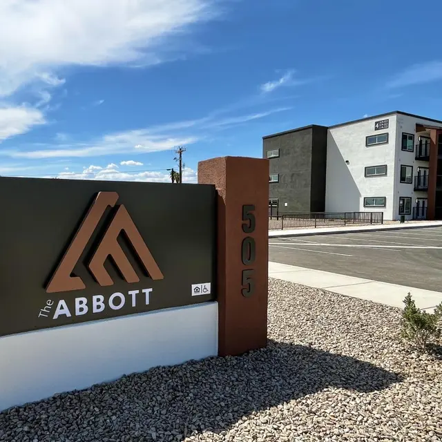 Entrance Sign of The Abbott Apartment Complex Sign for The Abbott with modern apartment buildings in the background under a blue sky.