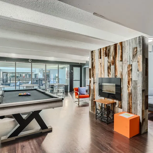 A modern game room featuring a pool table, cozy seating, and a decorative wall.
