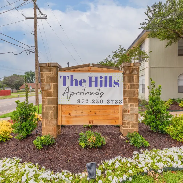 The Hills - Sign for The Hills Apartments with a landscaped garden in front, featuring flowers and greenery.