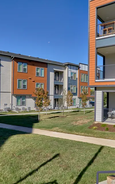 A view of a modern apartment complex with colorful exteriors, showcasing multiple buildings and a well-maintained green lawn.