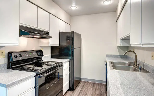 Modern kitchen with white cabinetry and stainless steel appliances including a stove, refrigerator, and sink.
