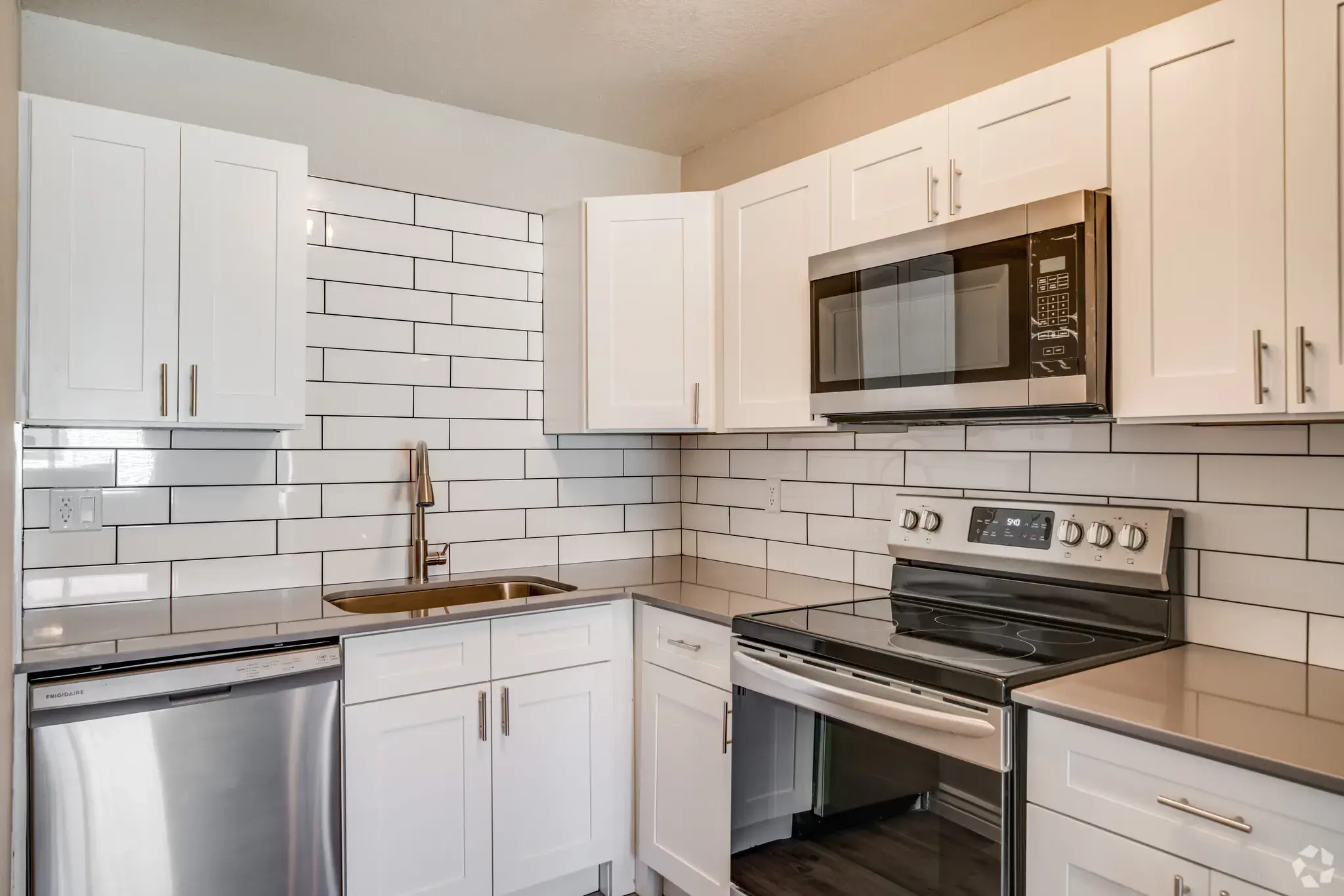 Modern Kitchen with White Cabinets and Stainless Steel Appliances A modern kitchen featuring white cabinetry, stainless steel appliances, and a sleek backsplash with white tiles.