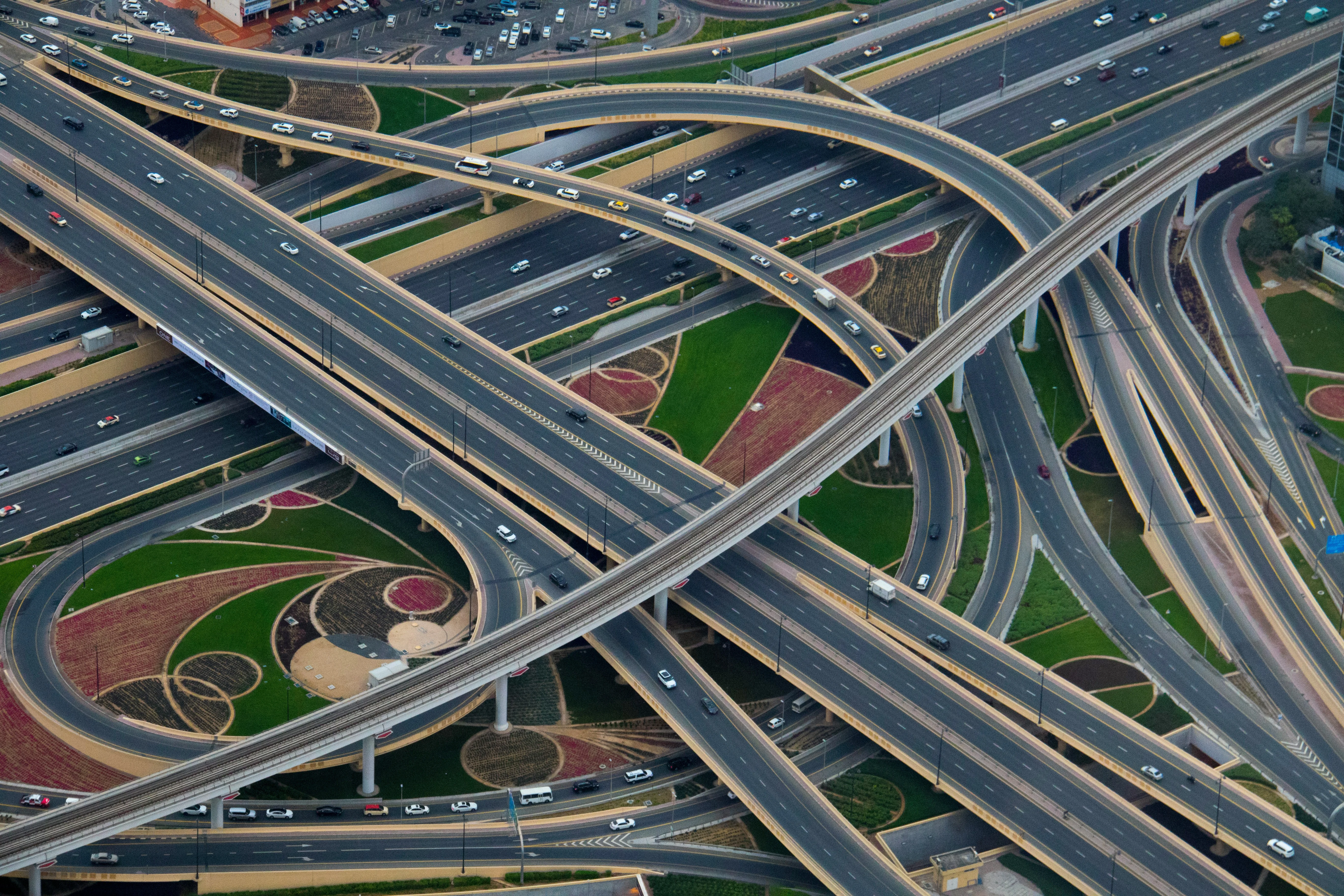 Aerial view of a complex highway interchange with multiple roadways and green landscaping underneath.