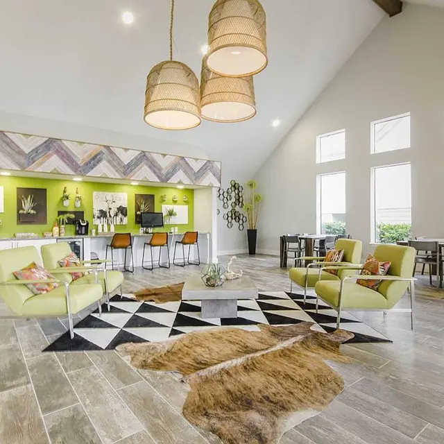 The Edge Apartments Large open resident clubhouse with four lime green chairs in the center and two tables and chairs in well lit space.