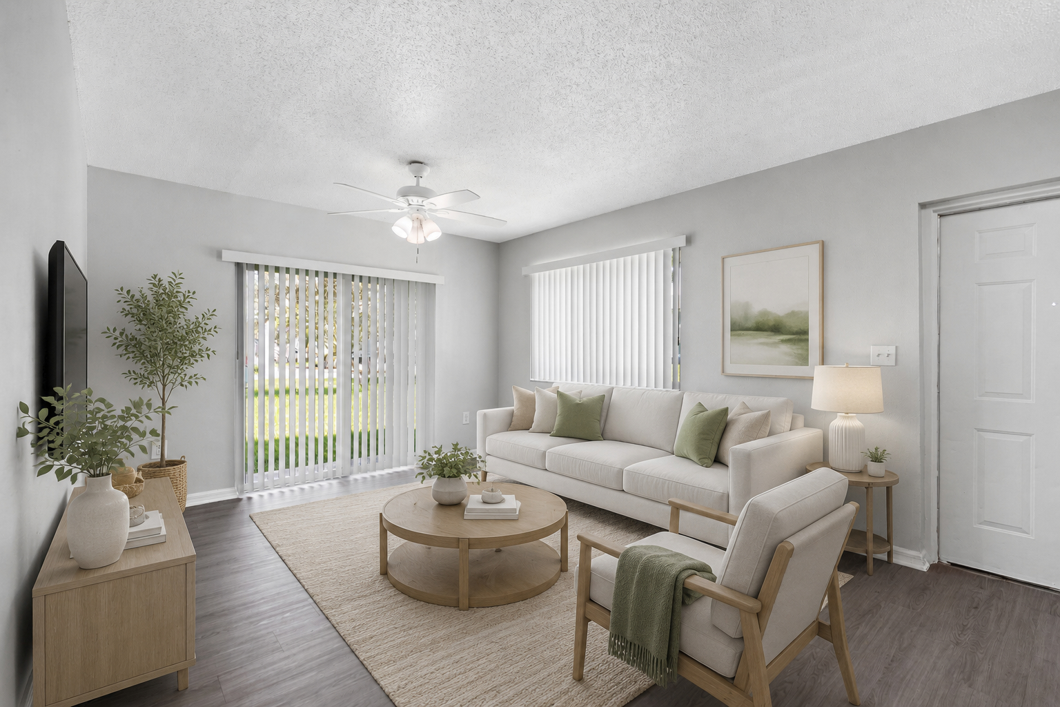 Modern Living Room Design A well-lit living room featuring a light gray color scheme, a comfortable sofa with green accents, a wooden coffee table, and a small plant near a TV. The room includes large windows with blinds and a glass door leading outside.