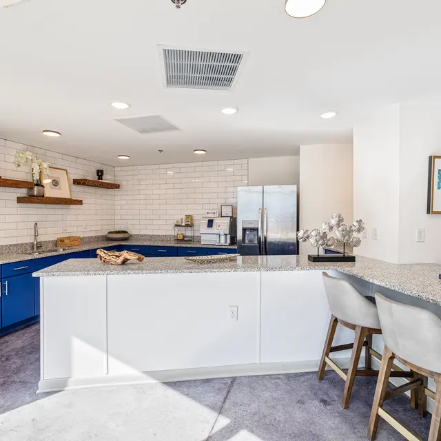 Modern Kitchen Design A modern kitchen with blue cabinetry and a gray countertop, featuring a stainless steel refrigerator and open shelving with decorative items.