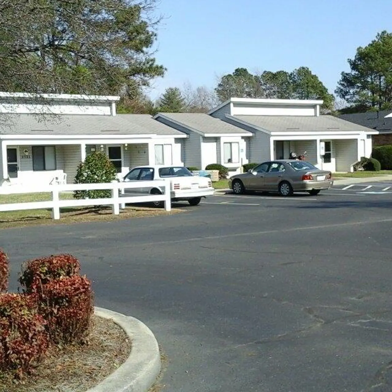 View of a residential area featuring single-story homes and parked cars on a sunny day.