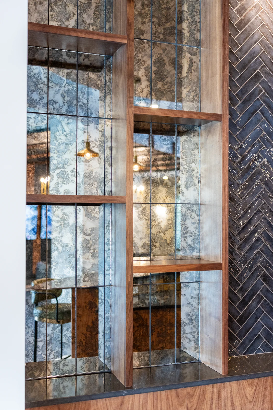 Contemporary Shelving Unit A close-up of a modern shelving unit featuring mirrored glass panels, wooden shelves, and a decorative wall with a patterned design.