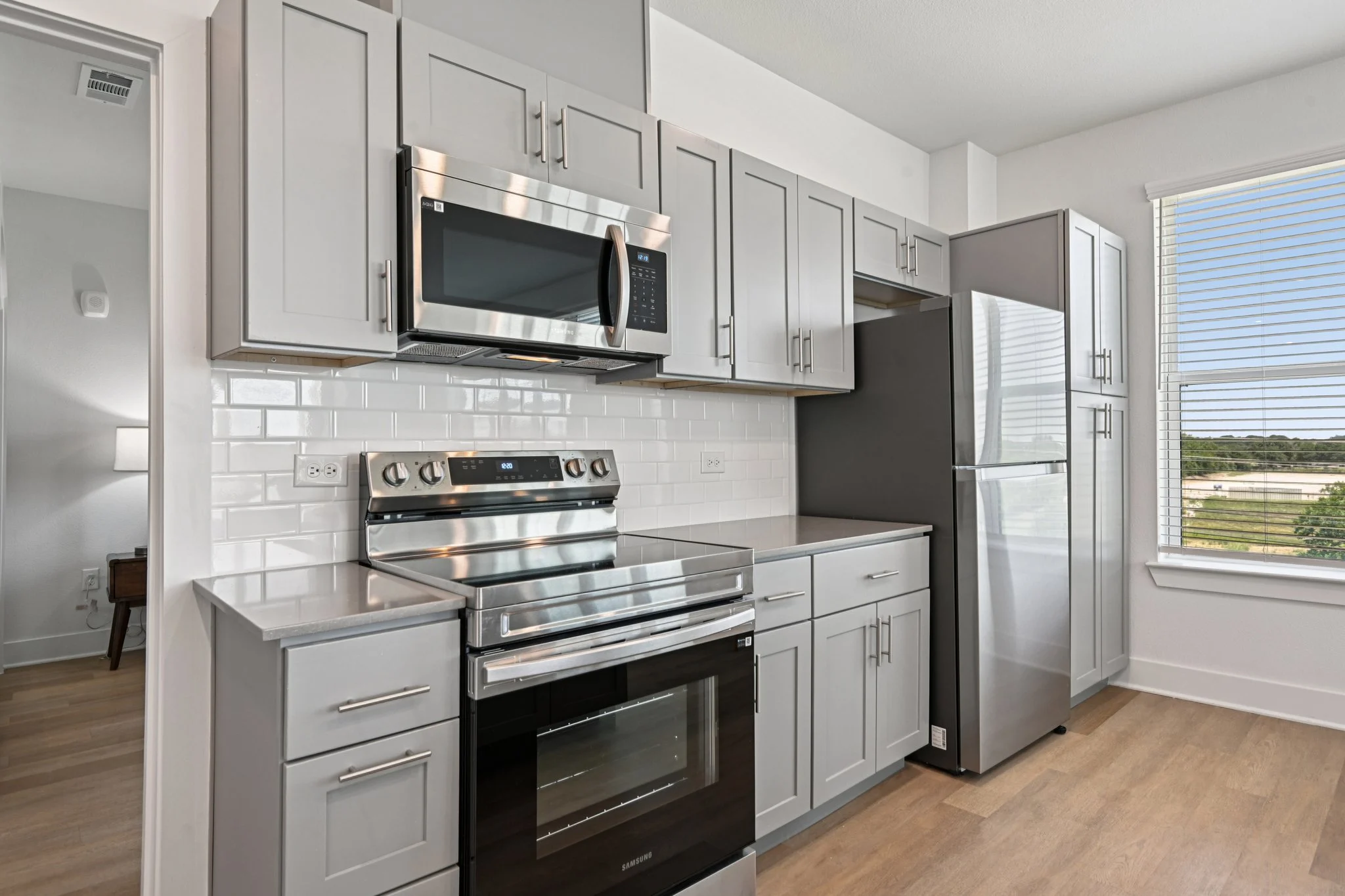 Stylish Modern Kitchen A modern kitchen featuring gray cabinets, stainless steel appliances, and a large window with a view.