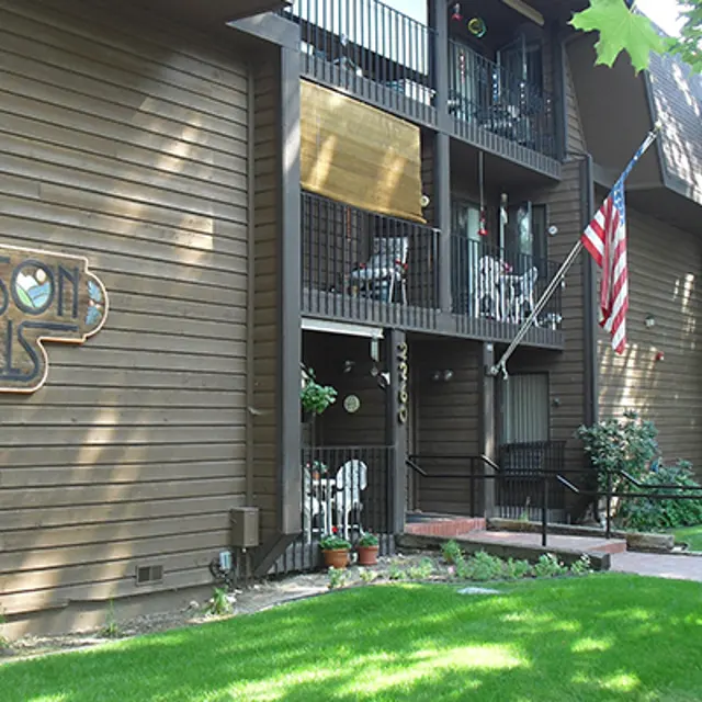 Exterior view of Harrison Hills apartment building with an American flag and green grass in front.
