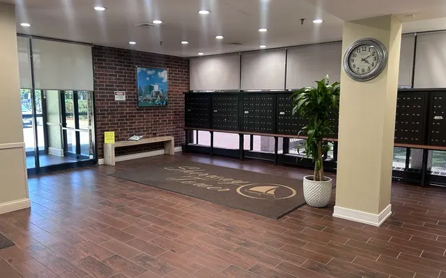 Community Lobby Interior Interior of a community lobby with mailboxes and a clock, featuring a plant and a welcome mat.