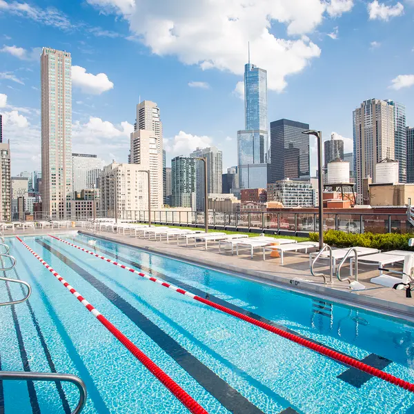 Rooftop pool with lanes, surrounded by city skyscrapers and a clear blue sky. Relaxing urban skyline view.