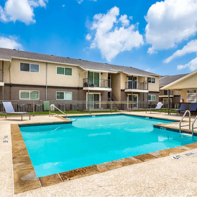 North Star Apartments pool surrounded by blue lawn chairs and apartments with balconies and patios in the background