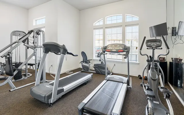 Modern Gym Interior A modern gym interior featuring various exercise equipment including treadmills, elliptical machines, and weight machines, with large windows allowing natural light to fill the space.