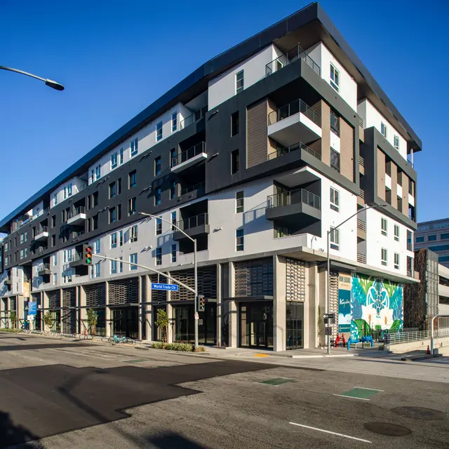 Modern Apartment Building A modern multi-story apartment building with a mix of colors and materials, featuring balconies and large windows, set on a street corner.