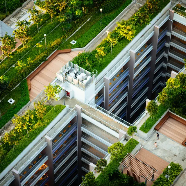 POST Houston Aerial view of a modern building complex with lush green landscaping, terraces, and walkways. The structures are arranged in a way that creates a harmonious blend of nature and architecture.