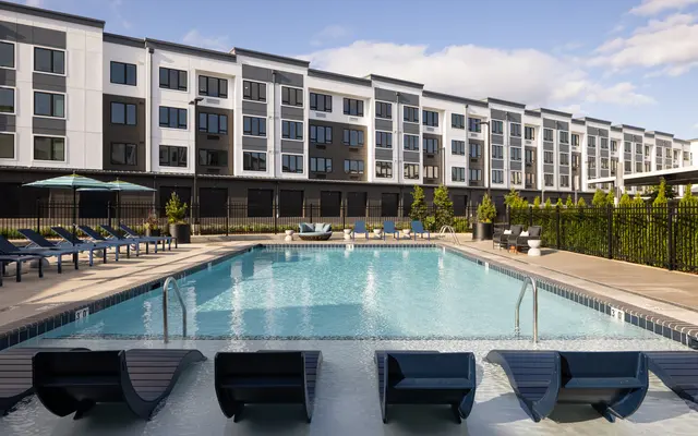 Modern Apartment Complex with Pool A modern apartment complex with a swimming pool and lounge chairs