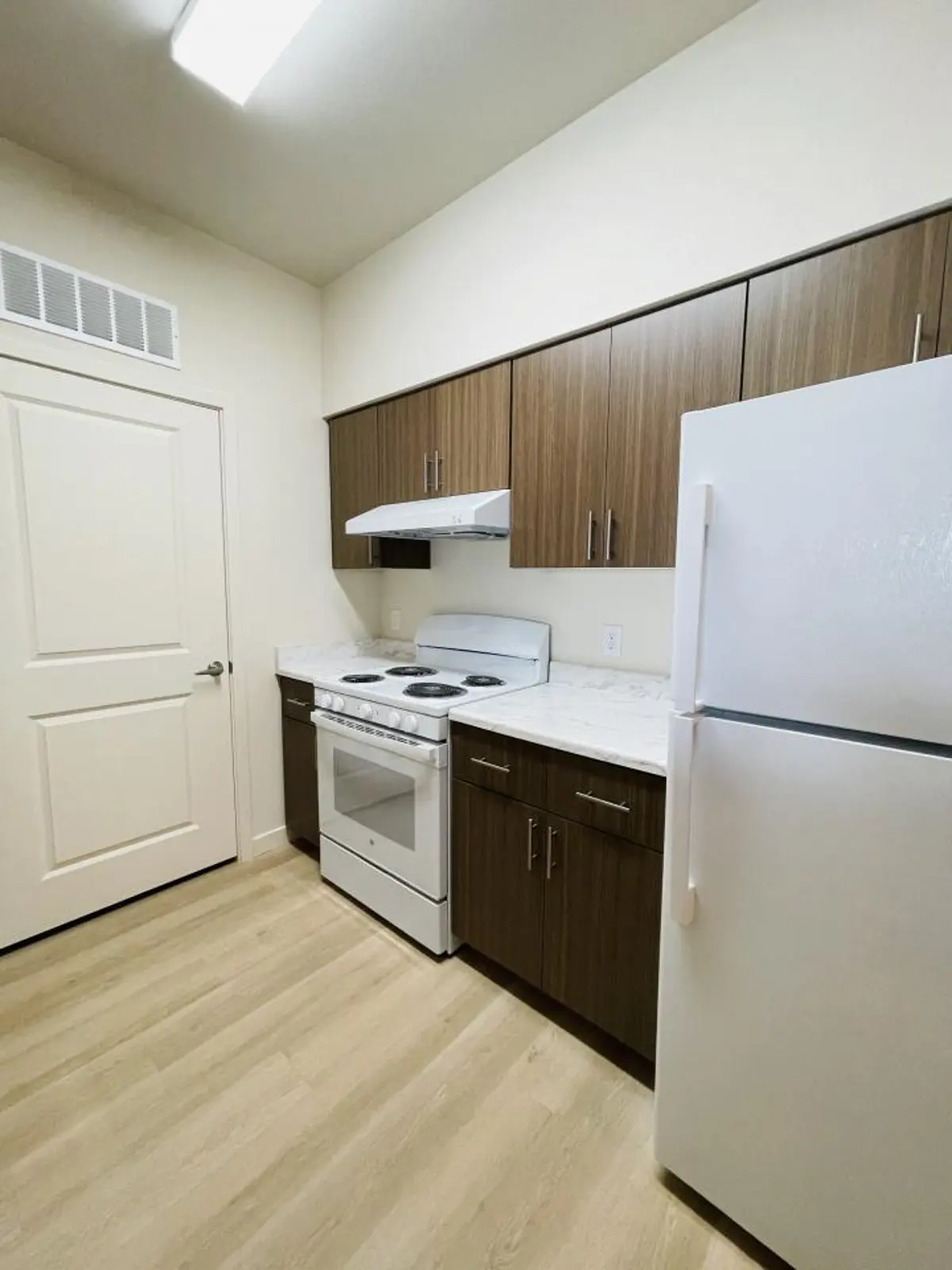 Galley kitchen with brown cabinets and white appliances.