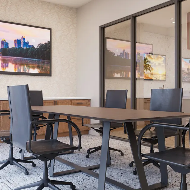 An interior view of a modern conference room featuring a large table surrounded by black office chairs. On the walls, two framed images of cityscapes are visible. The room includes glass partitions and warm wooden cabinetry, creating a professional atmosphere.
